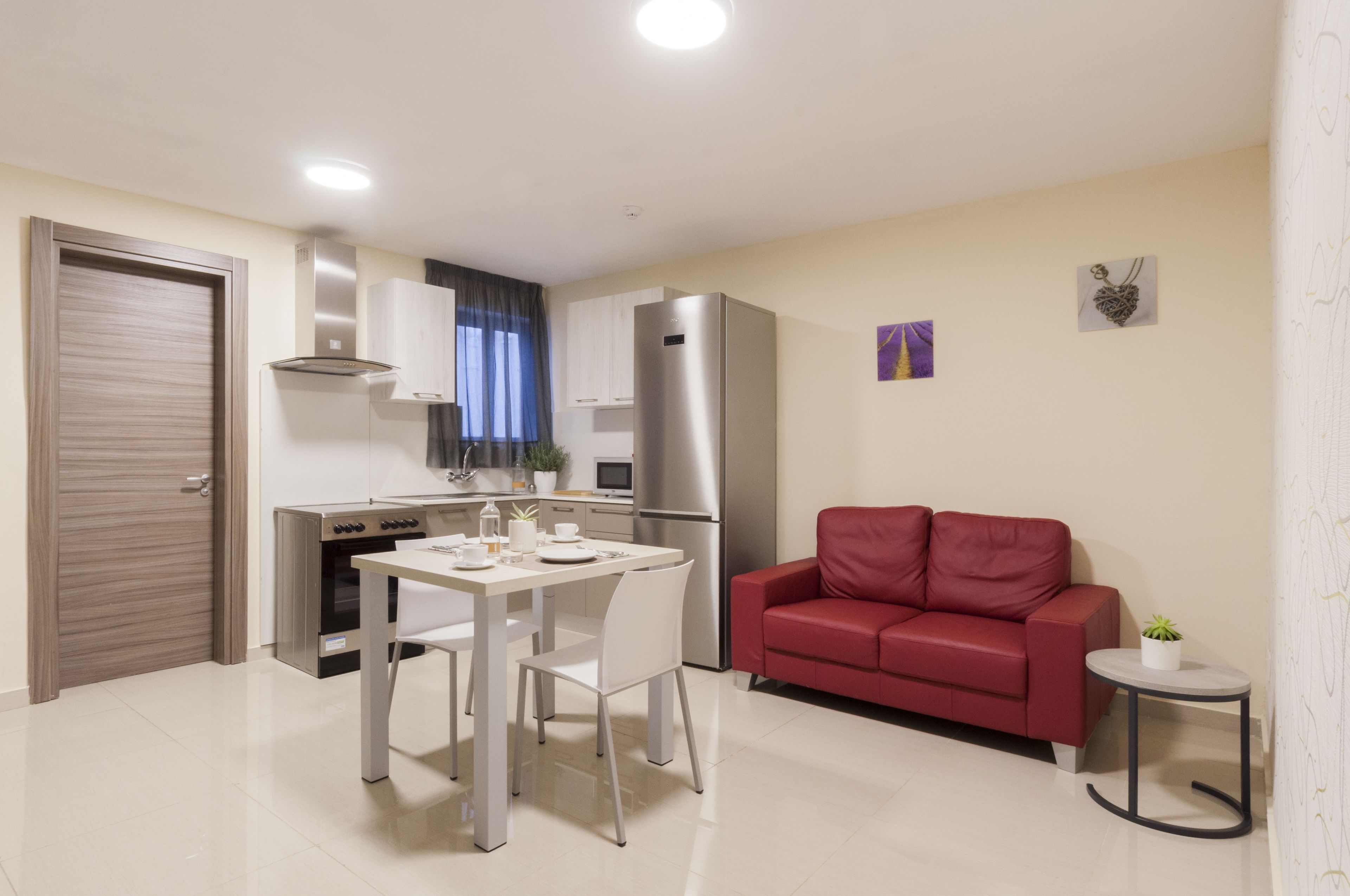 A compact living space with a kitchenette, dining area, and a red sofa.