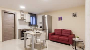 Un espacio habitable compacto con kitchenette, comedor y un sofá rojo.