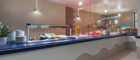 Mostrador de buffet con diversos alimentos y una planta en maceta.