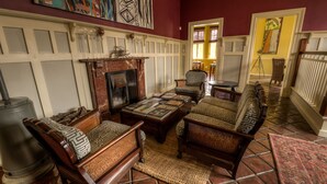 A traditional living room with a fireplace, patterned sofas, and a tiled floor. - Villa Margherita (Swakopmund)