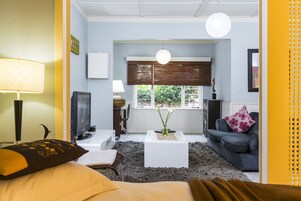 Una sala de estar moderna con un sofá, una mesa de centro, un televisor y una ventana con persianas.