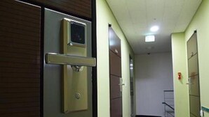 Un pasillo con puertas, una cámara de seguridad y un detector de incendios.