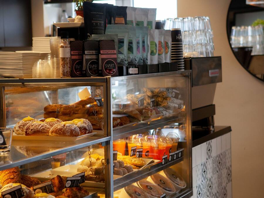Une vitrine de boulangerie remplie de diverses pâtisseries, avec un coin café en arrière-plan.