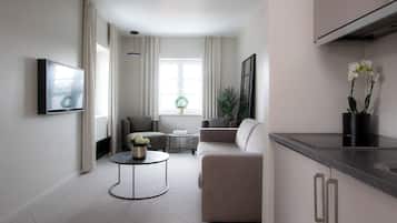 Un salón moderno con un sofá, una mesa de centro redonda y un televisor montado en la pared.