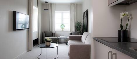 Un salón moderno con un sofá, una mesa de centro redonda y un televisor montado en la pared.