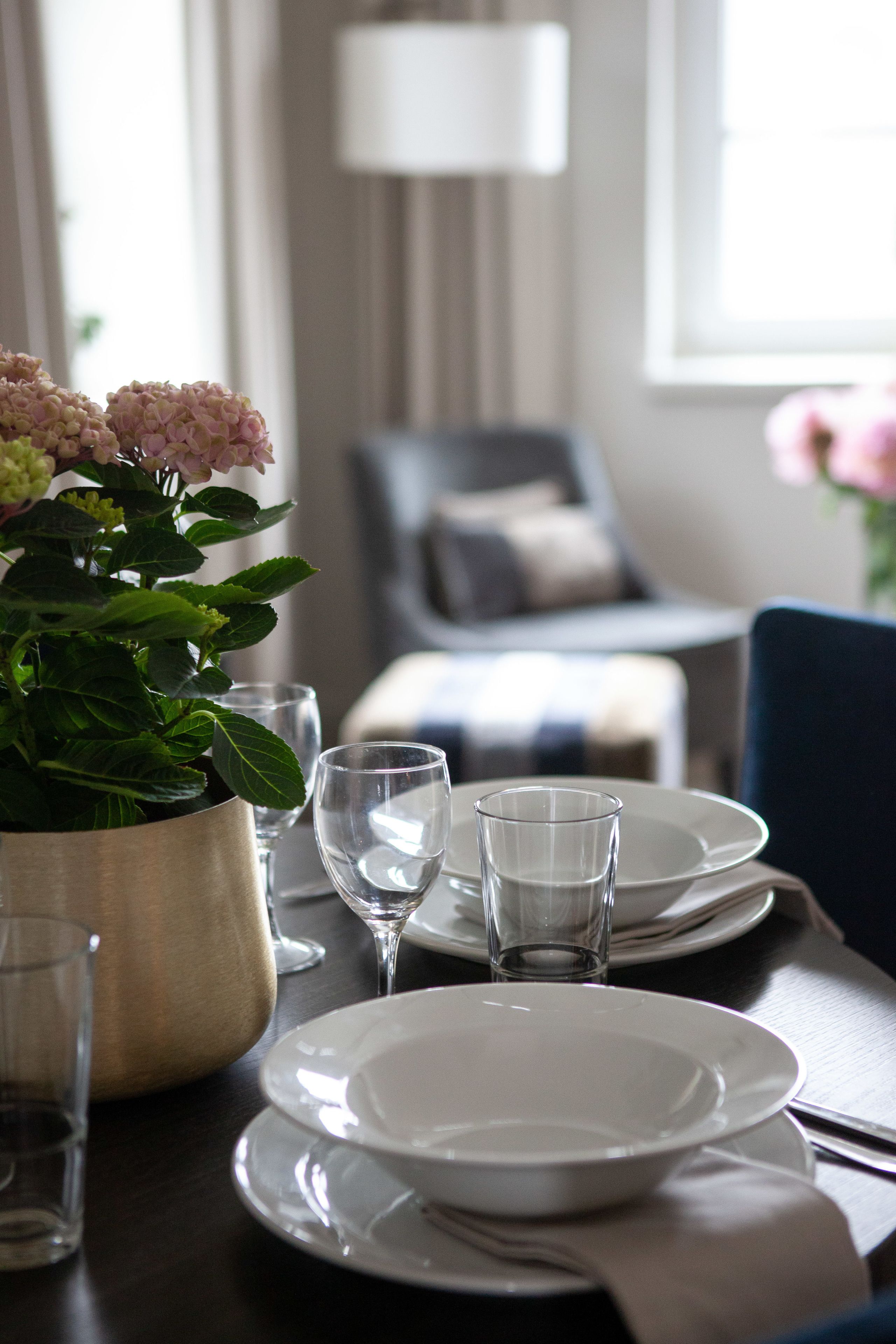 Una mesa puesta con platos, vasos y una planta en maceta.