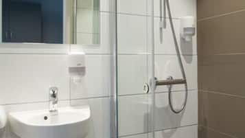 Een moderne badkamer met een douchecabine van glas, een witte wastafel en een spiegel erboven.
