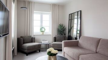 A modern living room with two sofas, a coffee table, a TV, and a large window with curtains.