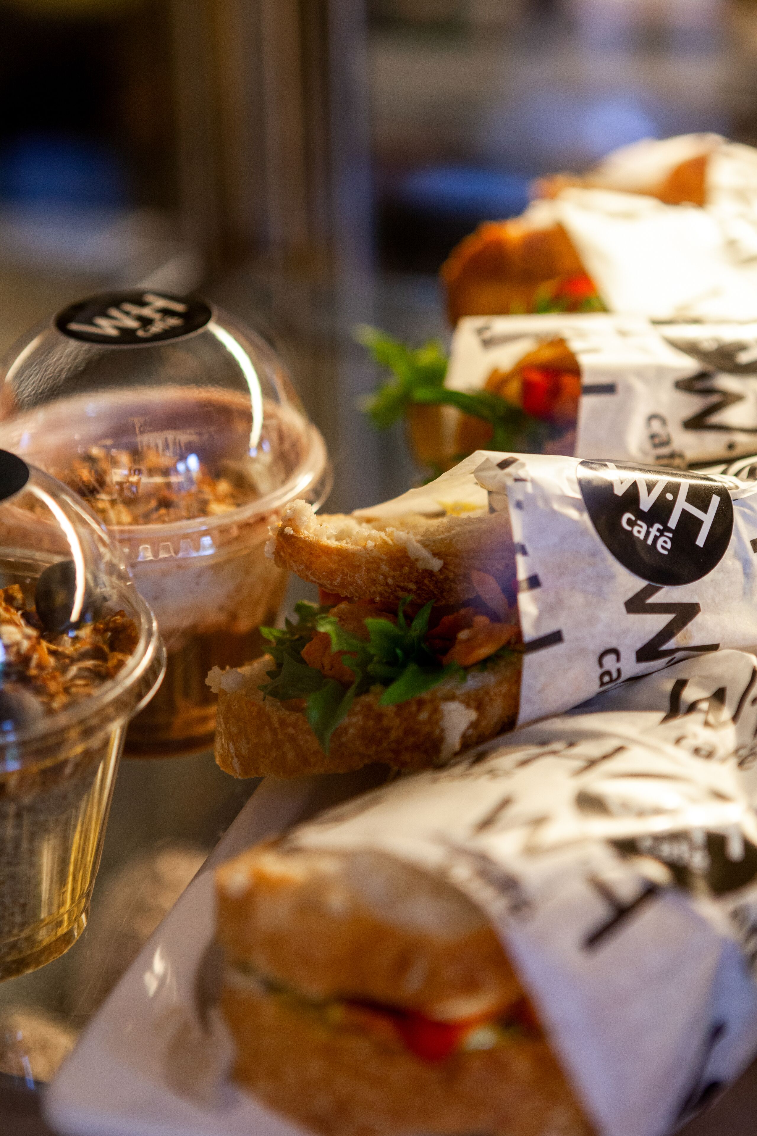 Un sándwich con ingredientes visibles y una etiqueta que dice 'W.H. cafe'.