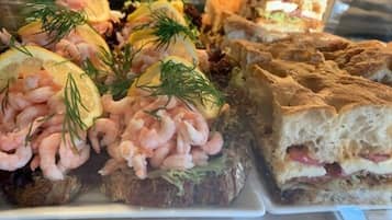 Variedad de alimentos, incluyendo camarones y sándwiches, probablemente parte de un bufé o servicio de catering.
