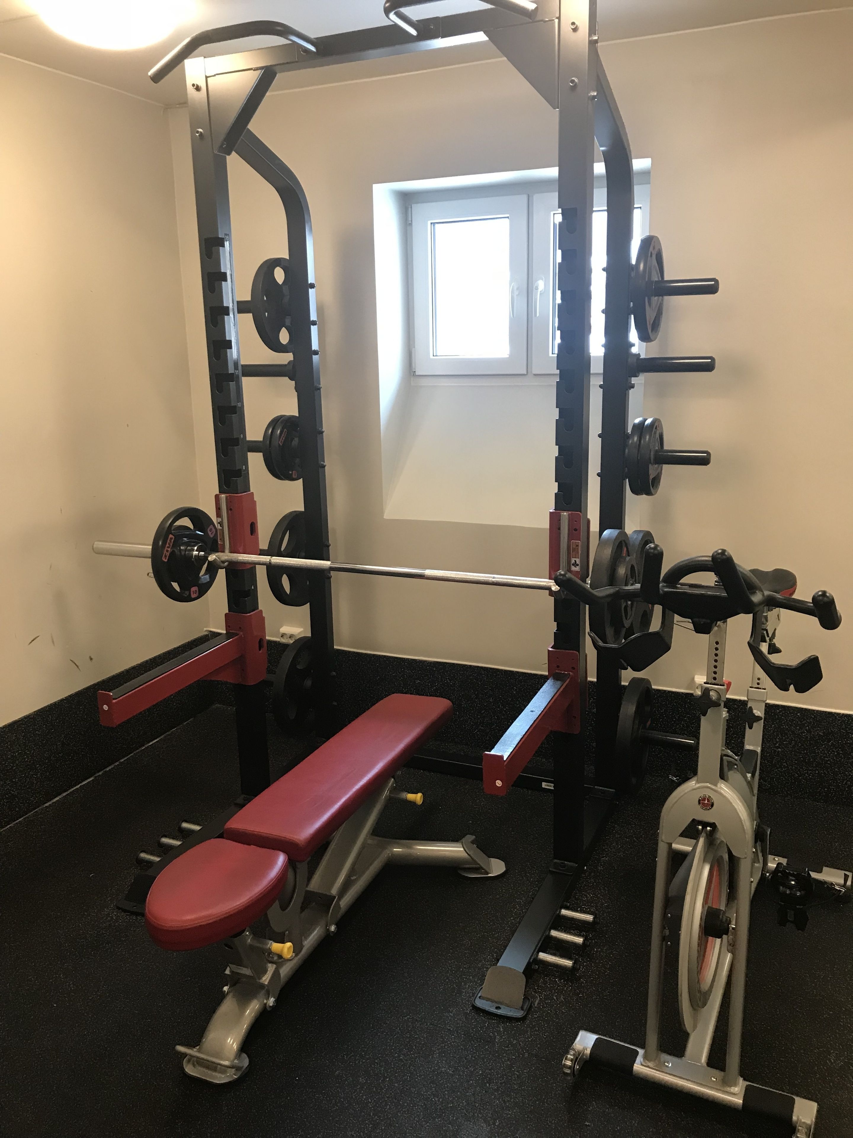 A gym with a bench, weight racks, and a stationary bike.
