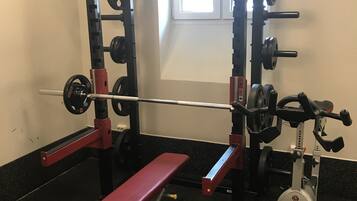 A gym with a bench, weight racks, and a stationary bike.
