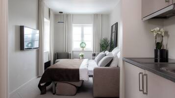 Un dormitorio moderno con una cama, mesitas de noche, un televisor y una ventana con cortinas.