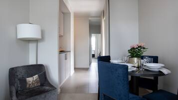 Un espace repas moderne avec une chaise à l’assise rembourrée de couleur bleu foncé, une table dressée avec des assiettes, des verres et une plante en pot.