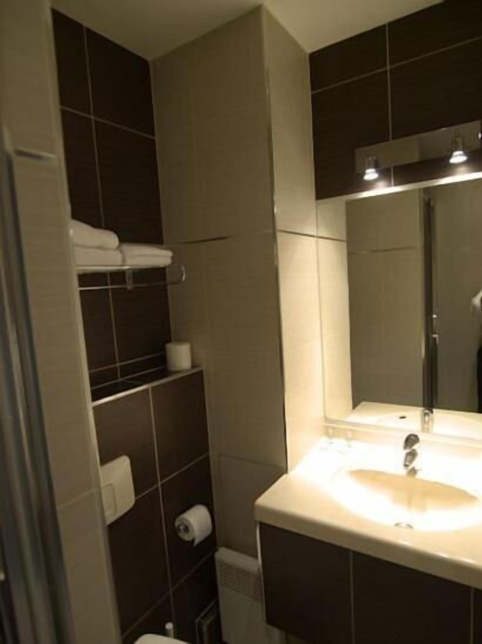 A modern bathroom with a large mirror, a sink, and a towel rack.