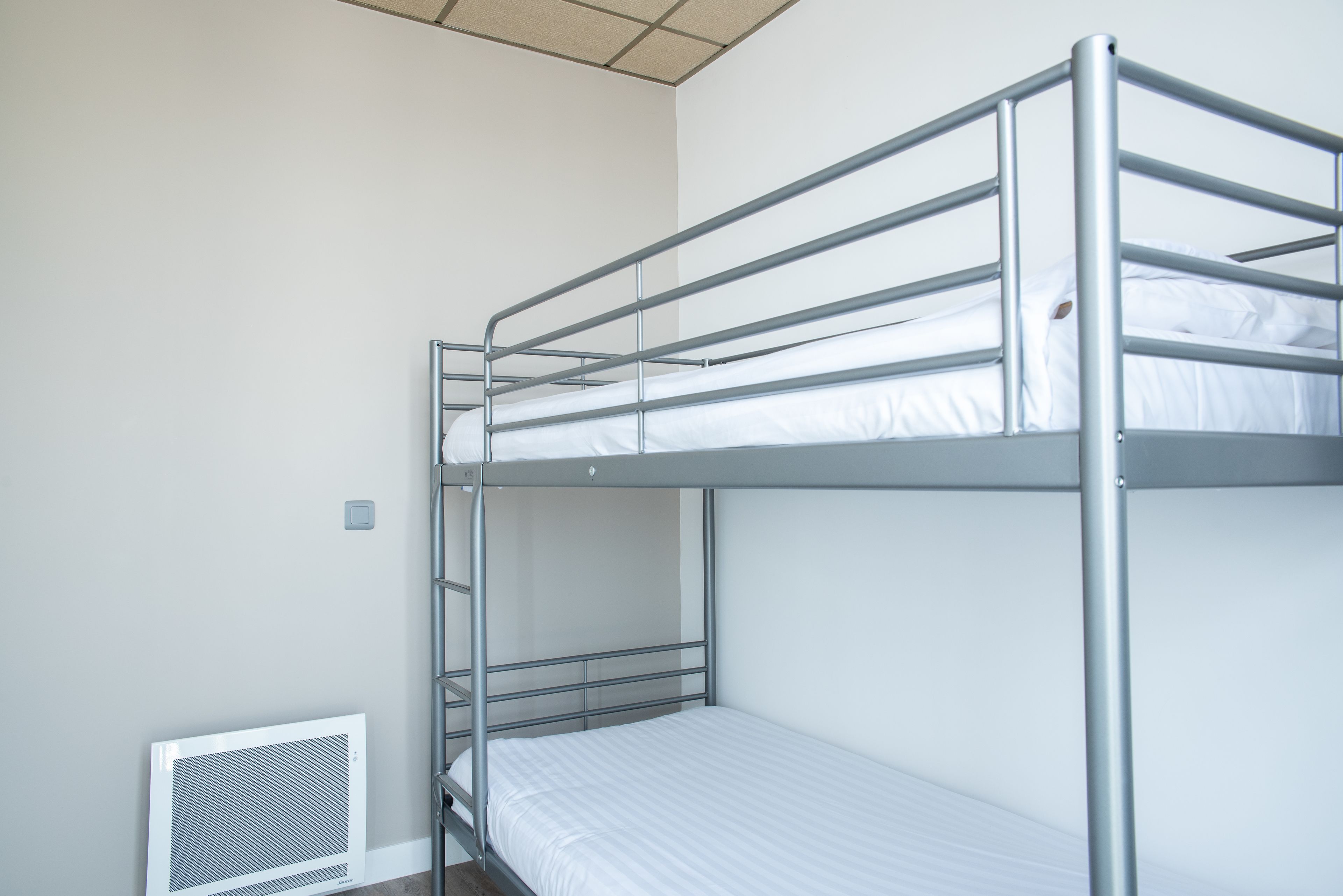 A bunk bed with metal railings and a white mattress.