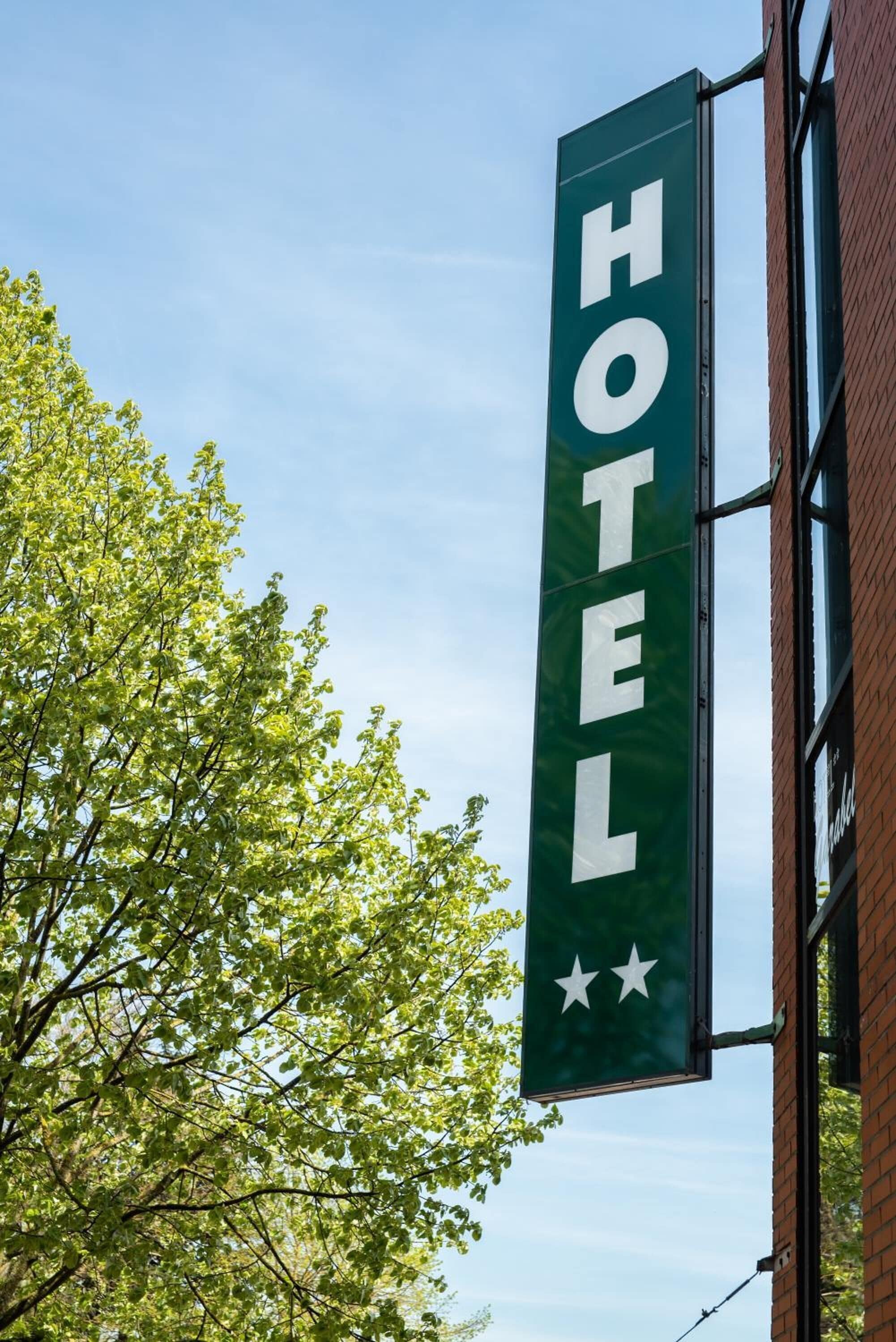 Placa vertical com a palavra 'HOTEL' e duas estrelas, fixada a um edifício.