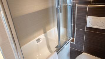 A modern bathroom with a glass shower enclosure, a white toilet, and a towel rack.