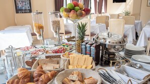 Une table de buffet proposant une variété d’aliments, notamment du pain, des pâtisseries, des fruits et des boissons.