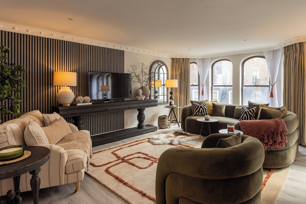 A modern living room with a sofa, armchairs, a coffee table, and a TV.