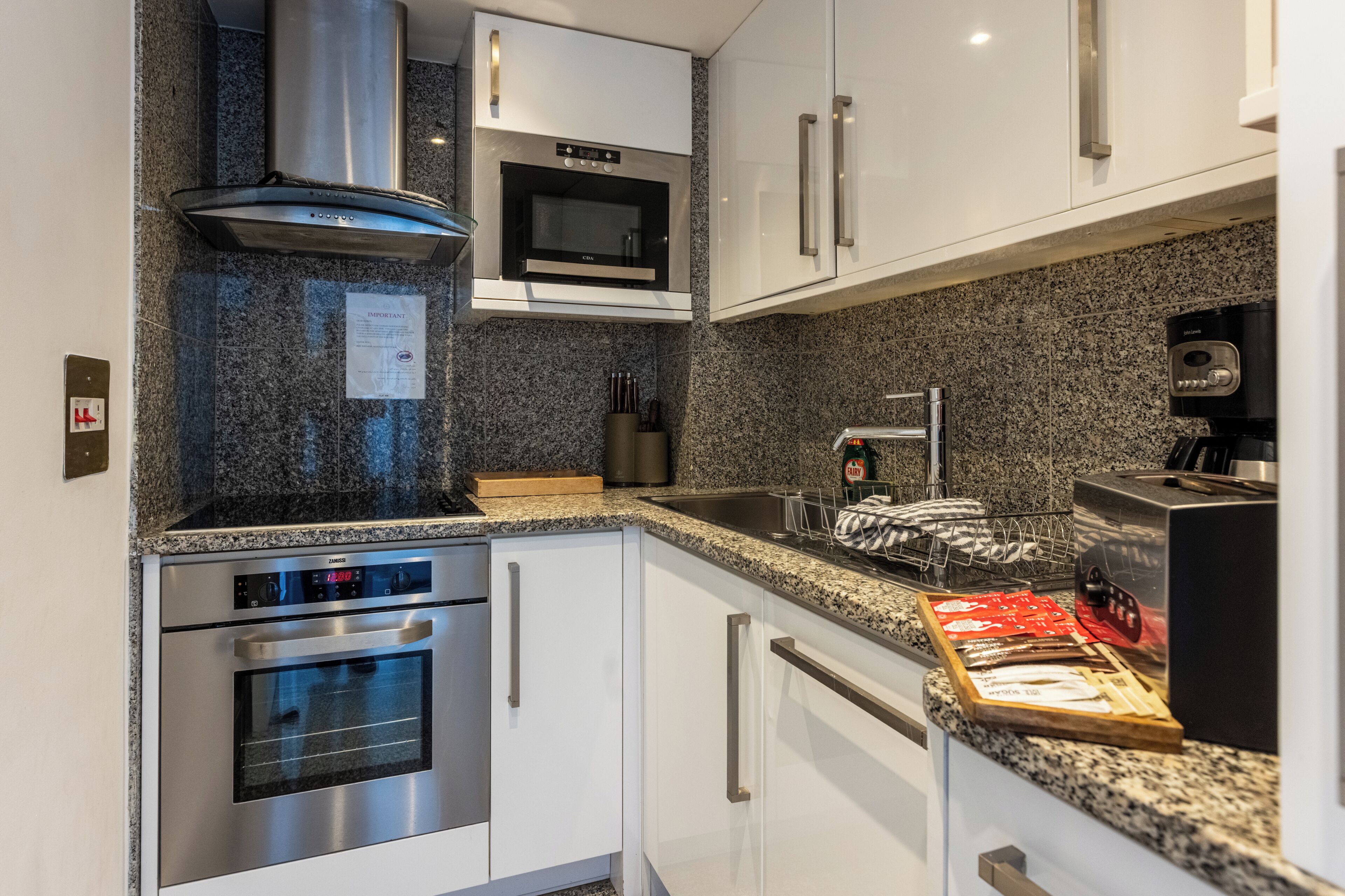 A modern kitchen with stainless steel appliances, granite countertops, and white cabinetry.