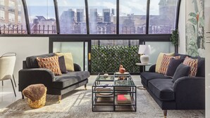 A modern living room with two black sofas, a glass coffee table, and a view of the city through large windows. - Mayfair House (London)