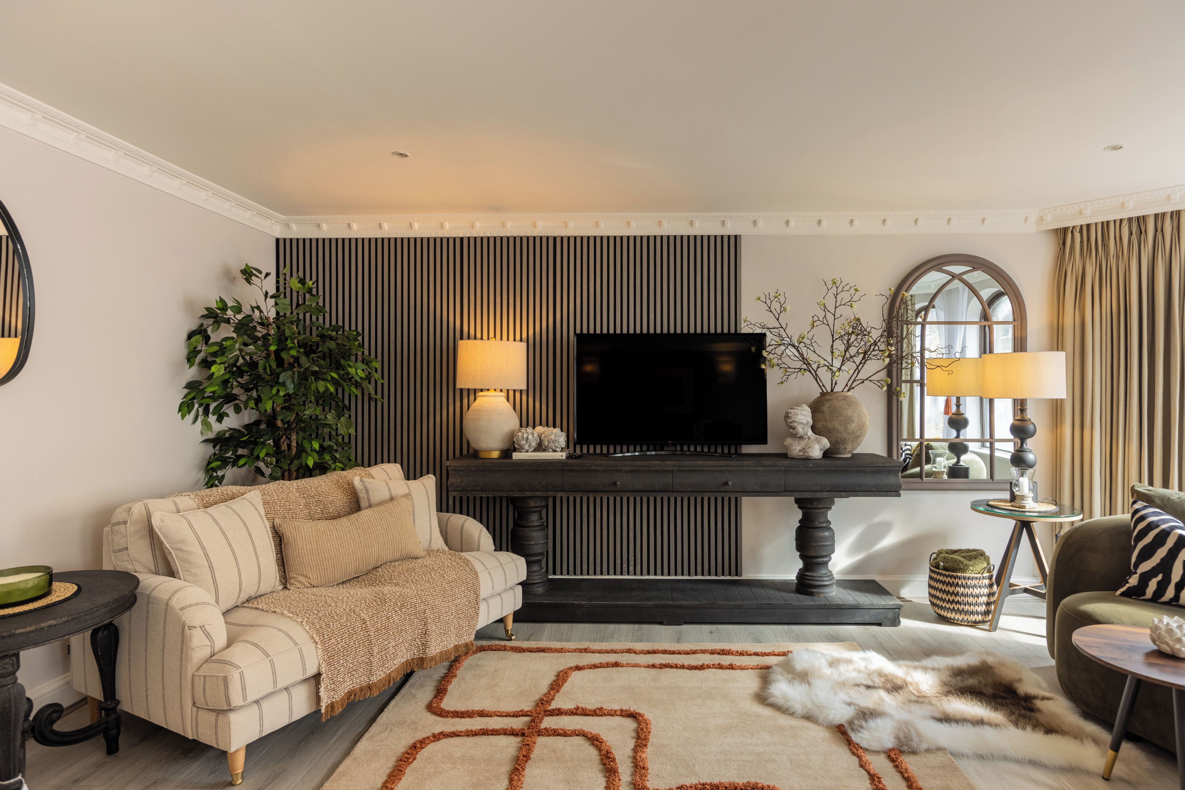 A living room with a sofa, a television, a fireplace, and a lamp.