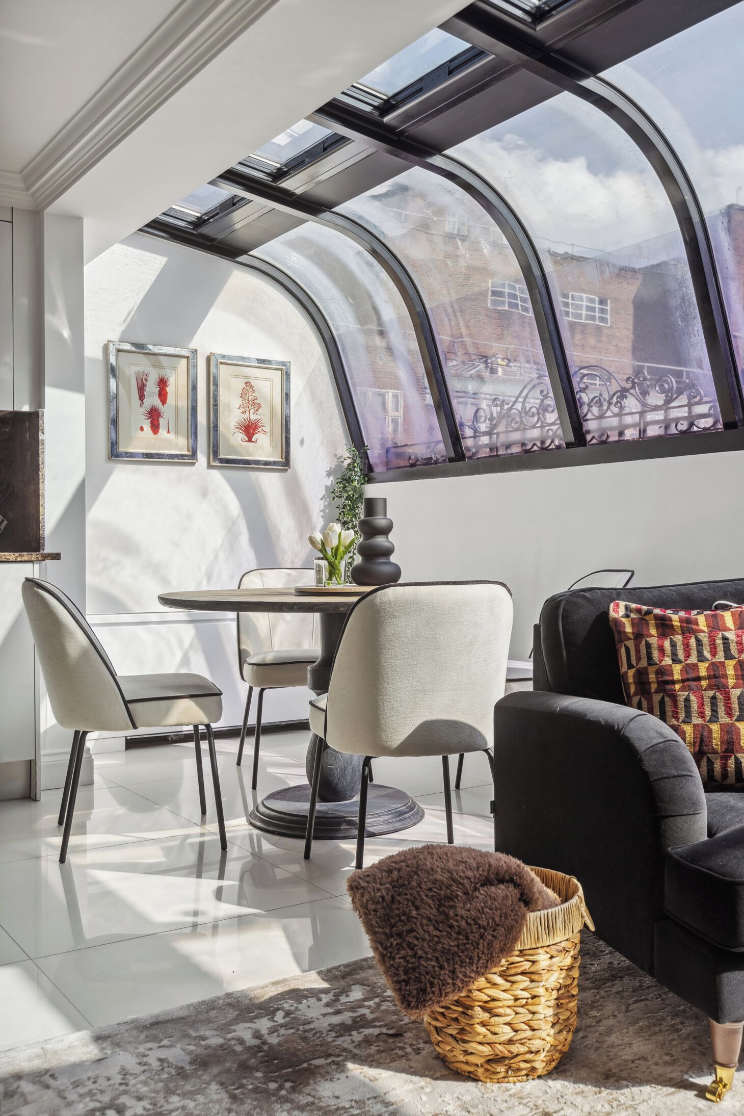 A modern living room with a curved skylight, a dining area, and a sofa with patterned cushions.