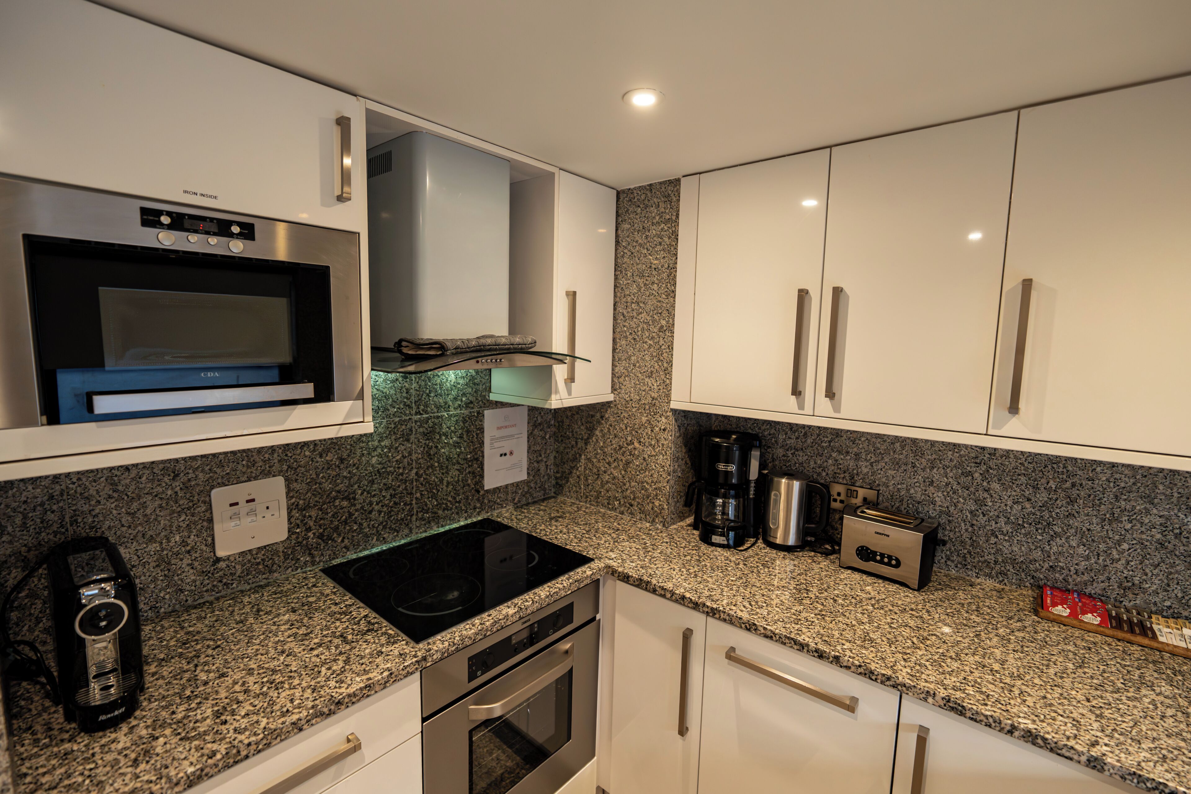 A kitchen with a built-in microwave, oven, and coffee maker.