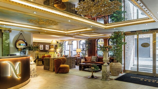 A hotel lobby with a reception desk, plush seating, a chandelier, and large windows. - Mayfair House (London)