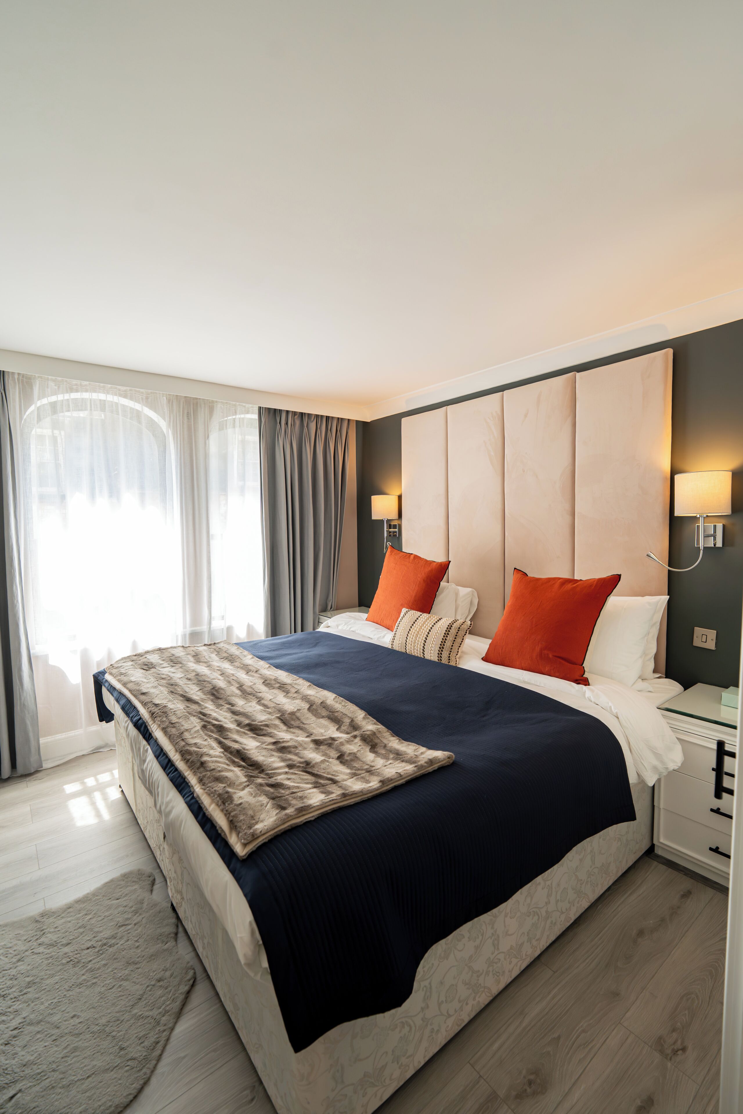 Une chambre d’hôtel moderne avec un grand lit, un tapis moelleux et une table de chevet avec une lampe.