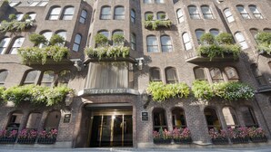 A multi-story building with a brick facade, large windows, and flower boxes on the balconies. - Mayfair House (London)