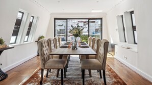 A dining area with a long table, multiple chairs, and a vase of flowers. - Mayfair House (London)