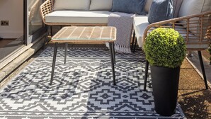A balcony with a sofa, a small table, and a potted plant. - Mayfair House (London)