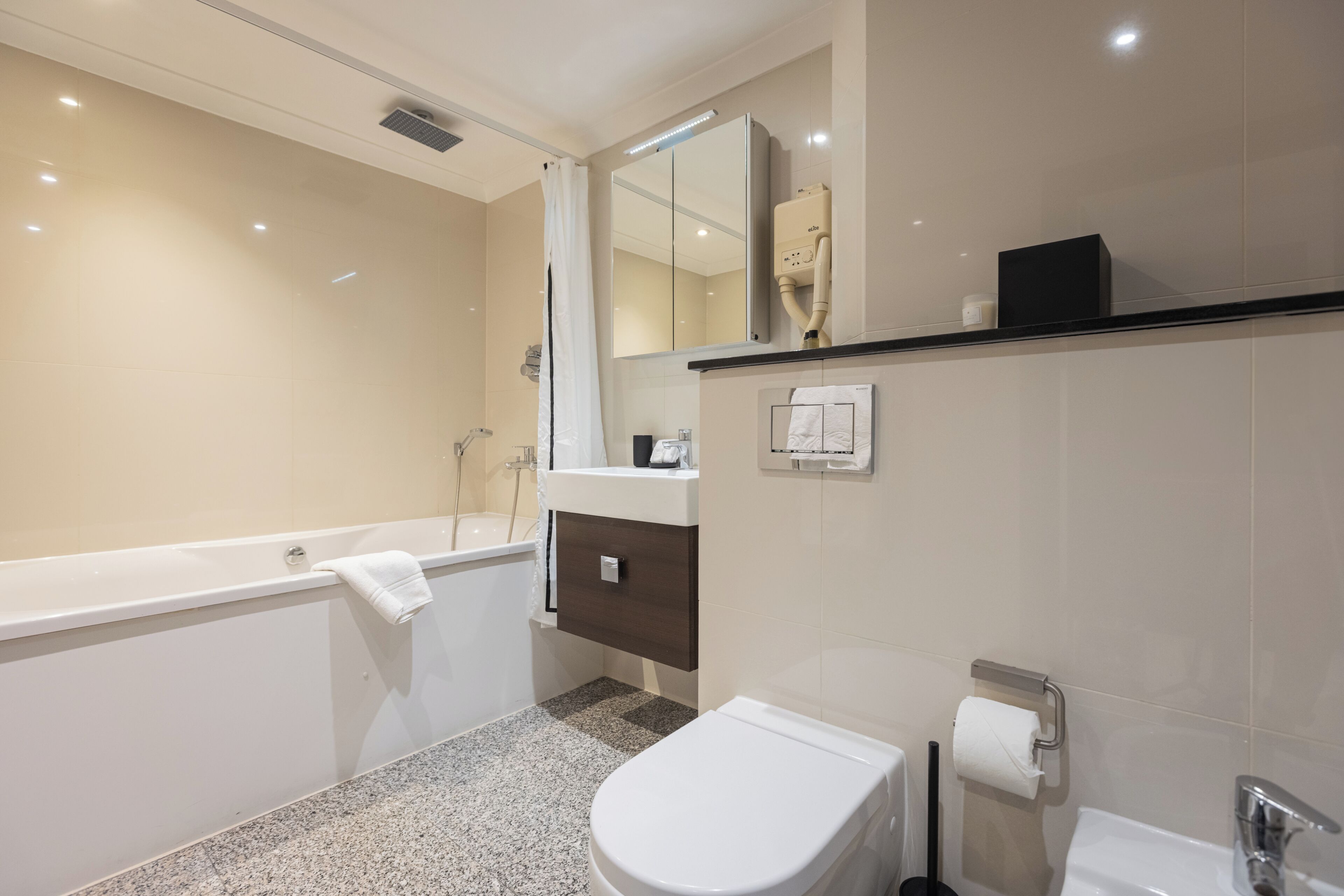A modern bathroom with a bathtub, toilet, and vanity.