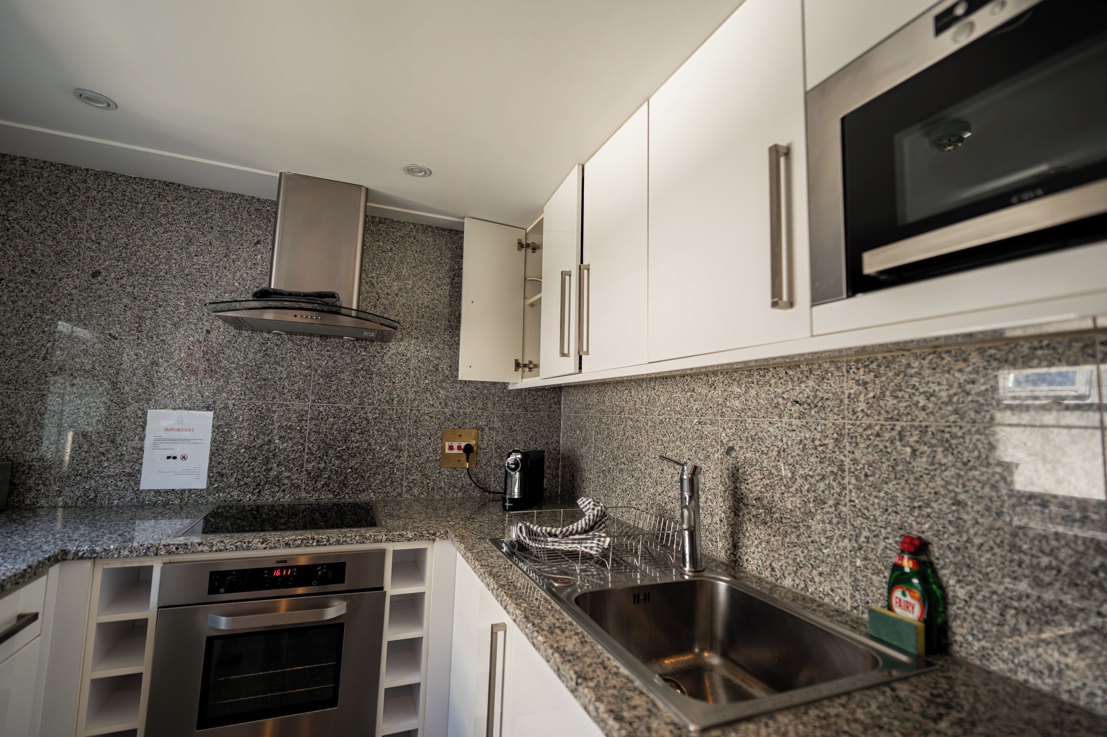 Una cocina moderna con encimeras de granito, electrodomésticos de acero inoxidable y armarios blancos.