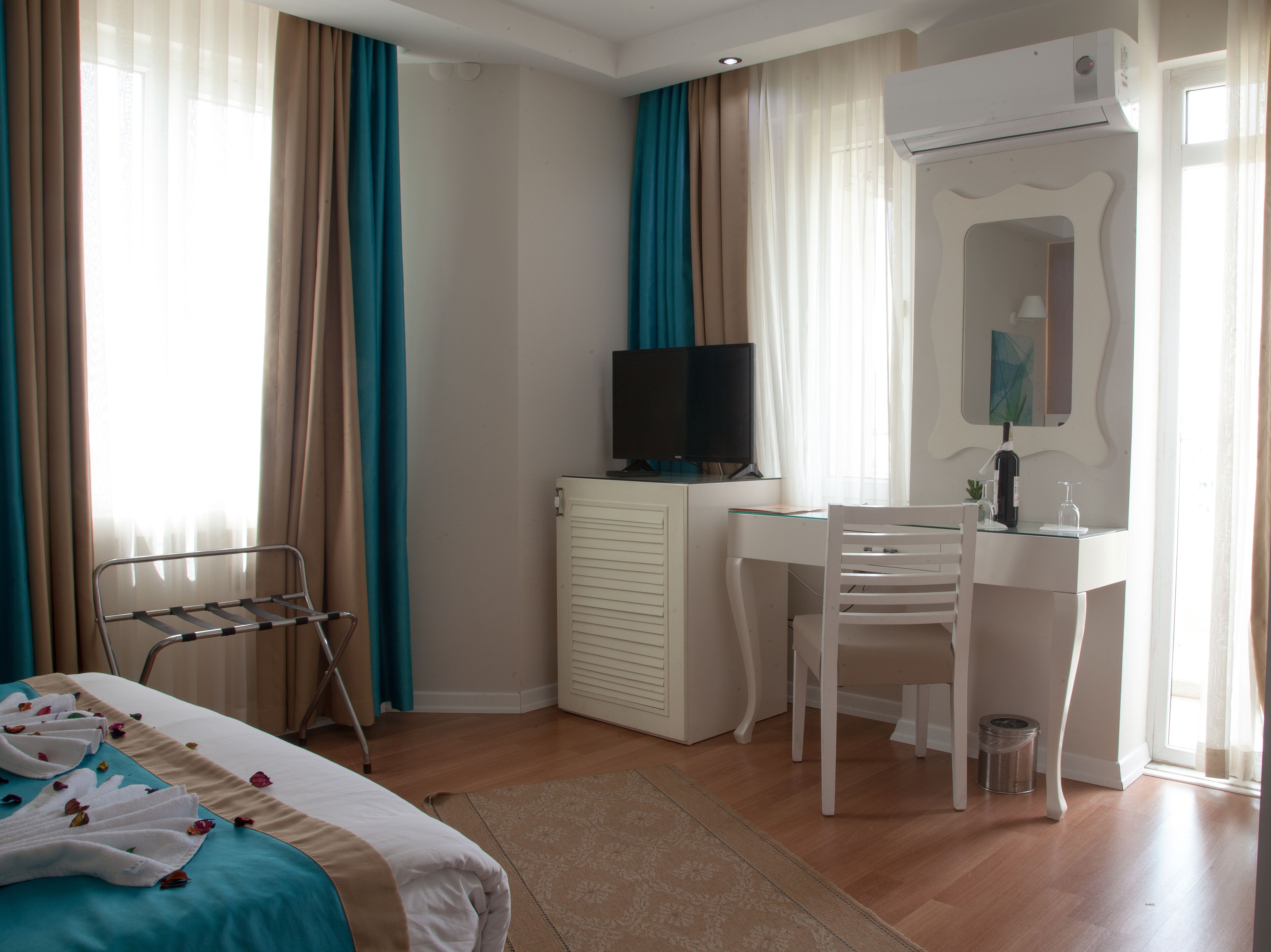 Habitación de hotel con cama, escritorio, silla, televisor y radiador.