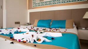 A hotel room with a bed covered in a blue bedspread, two blue pillows, and a white headboard. - Nasa Flora Hotel (Antalya)