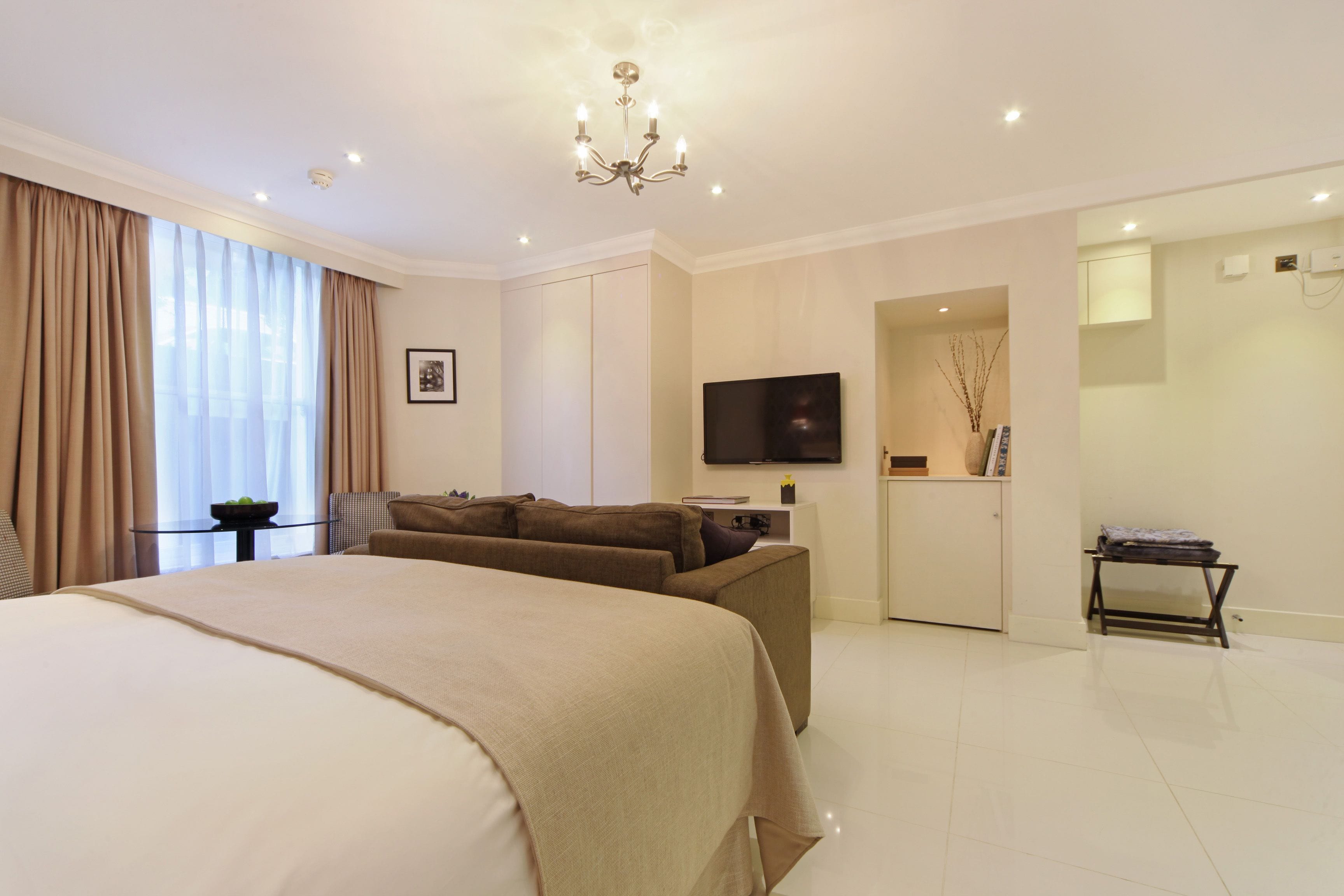 Ein modernes Hotelzimmer mit einem großen Bett, einer Couch, einem Fernseher und einem kleinen Tisch.