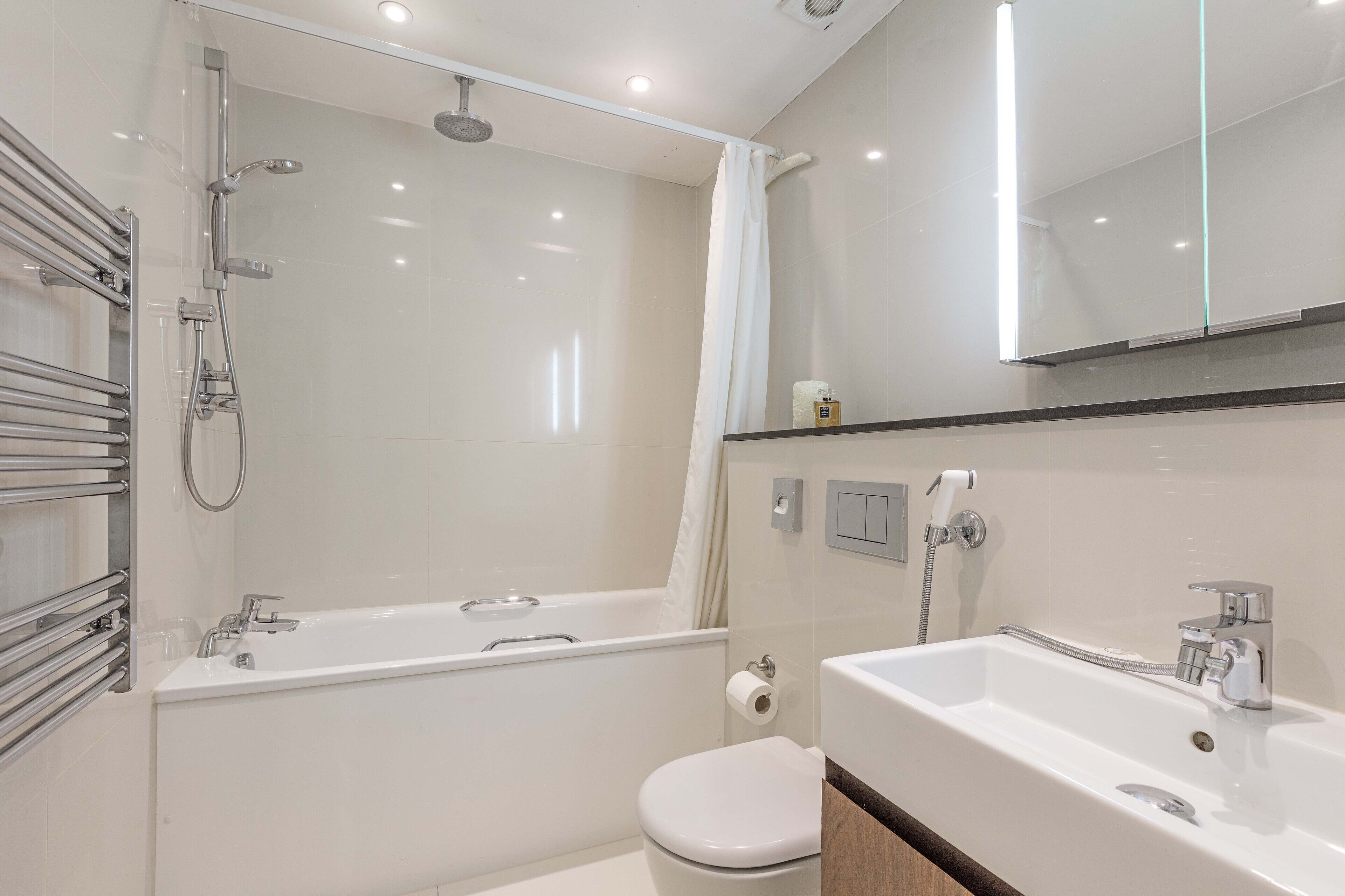 A modern bathroom with a glass-enclosed shower, a white bathtub, a sink, and a toilet.