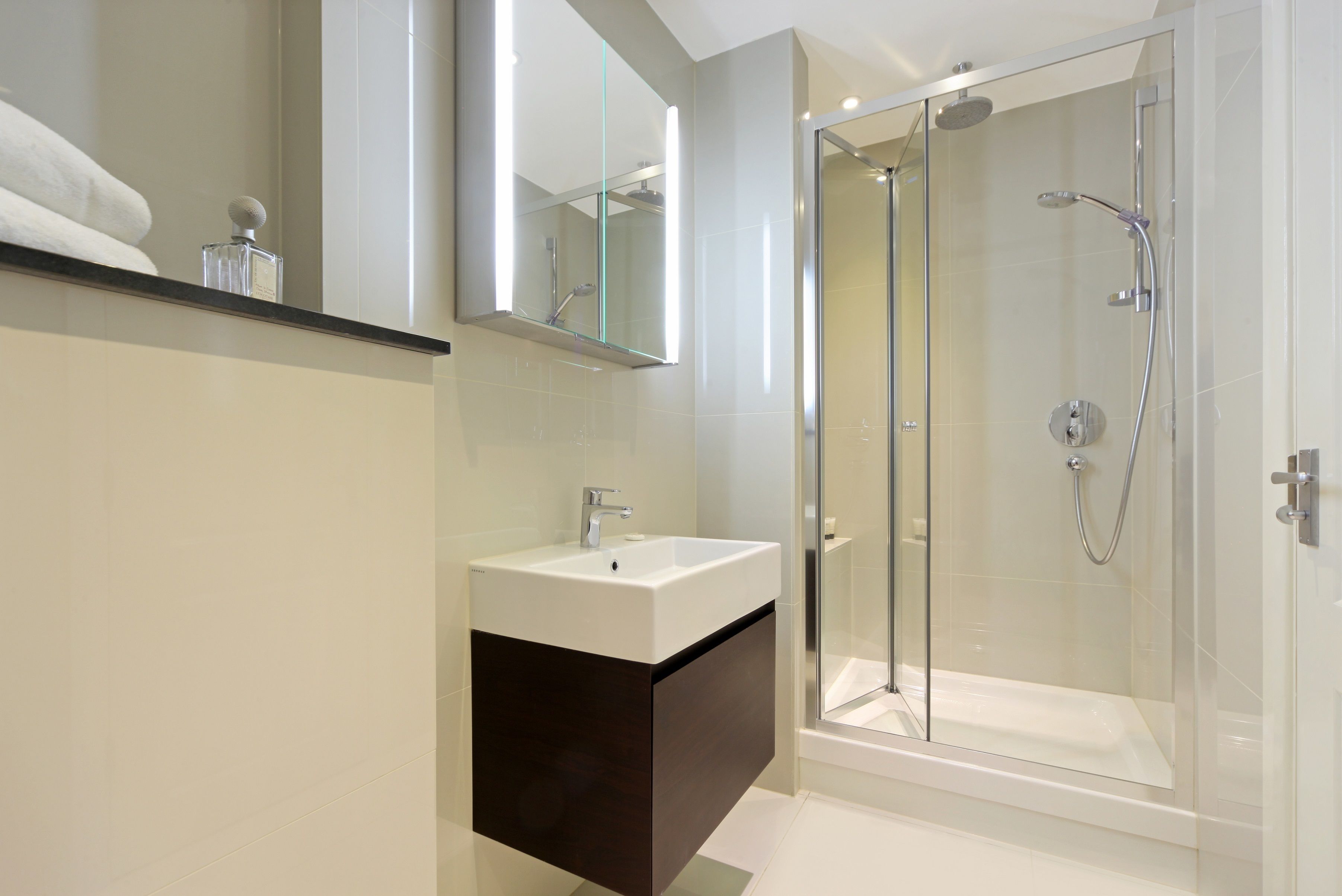 A modern bathroom with a glass-enclosed shower, a white sink, and a dark-toned vanity.