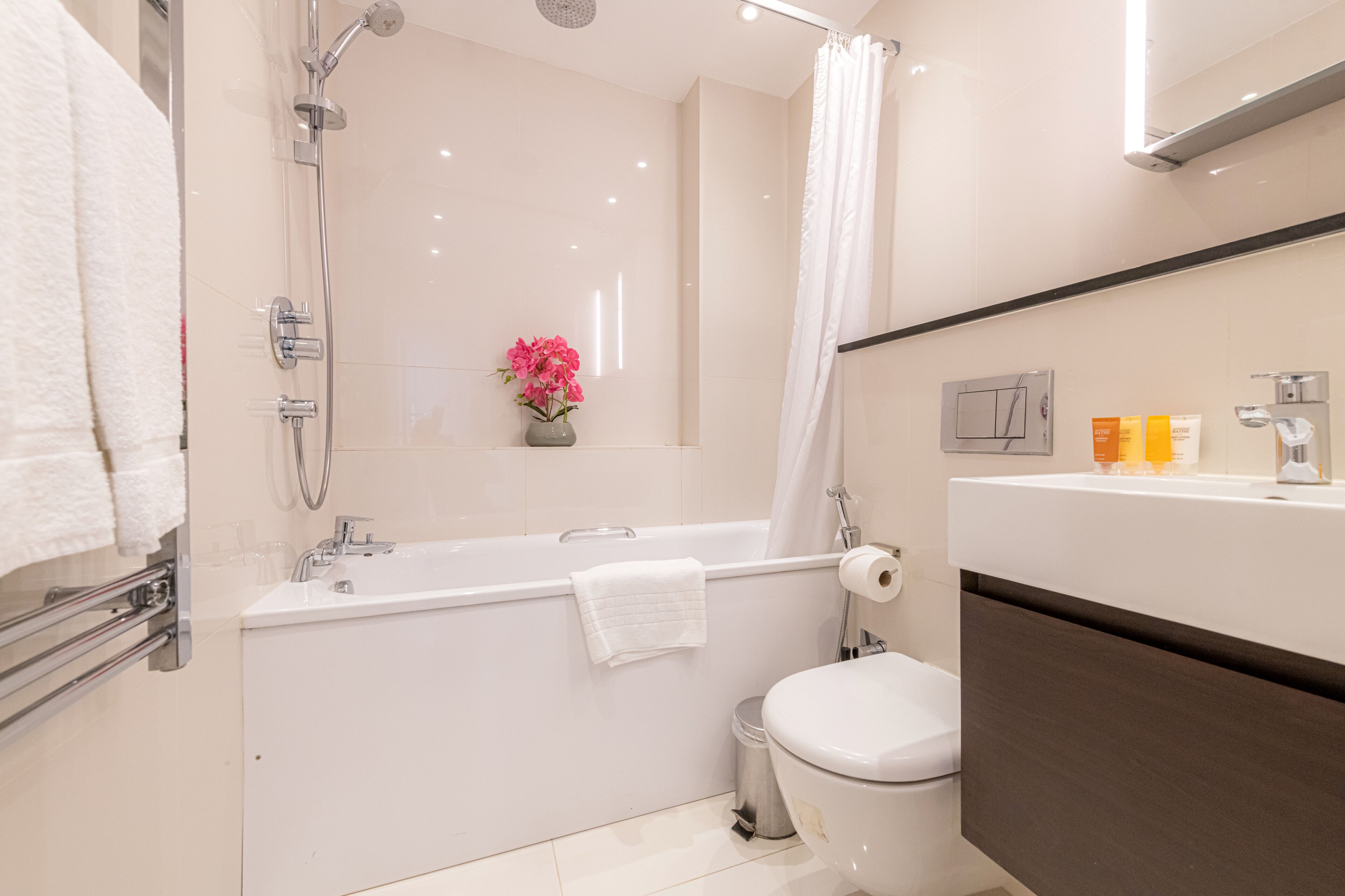 A modern bathroom with a bathtub, toilet, and a shower.