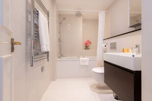 Une salle de bain moderne avec une douche à parois de verre, une baignoire blanche et un meuble-lavabo avec un miroir.