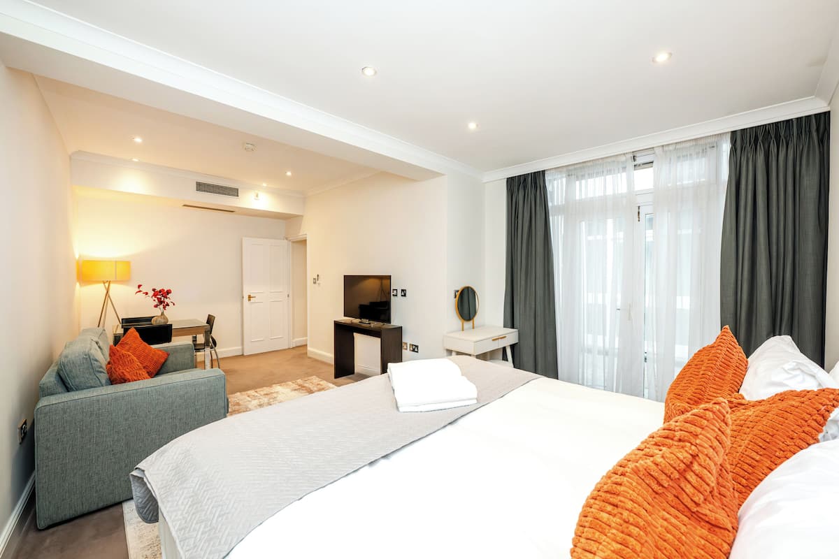 Quarto de hotel com cama, escrivaninha, cadeira, televisão e banheiro.