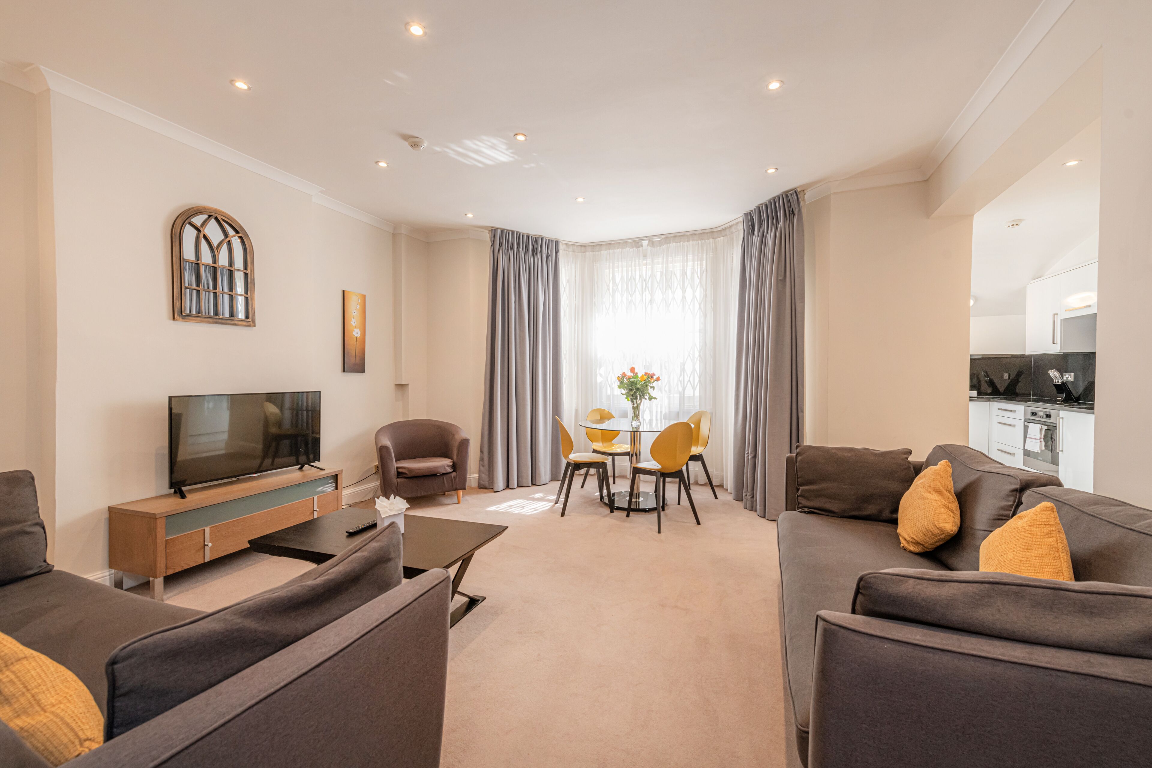 A modern living room with a sofa, TV, and dining area with chairs and a table.