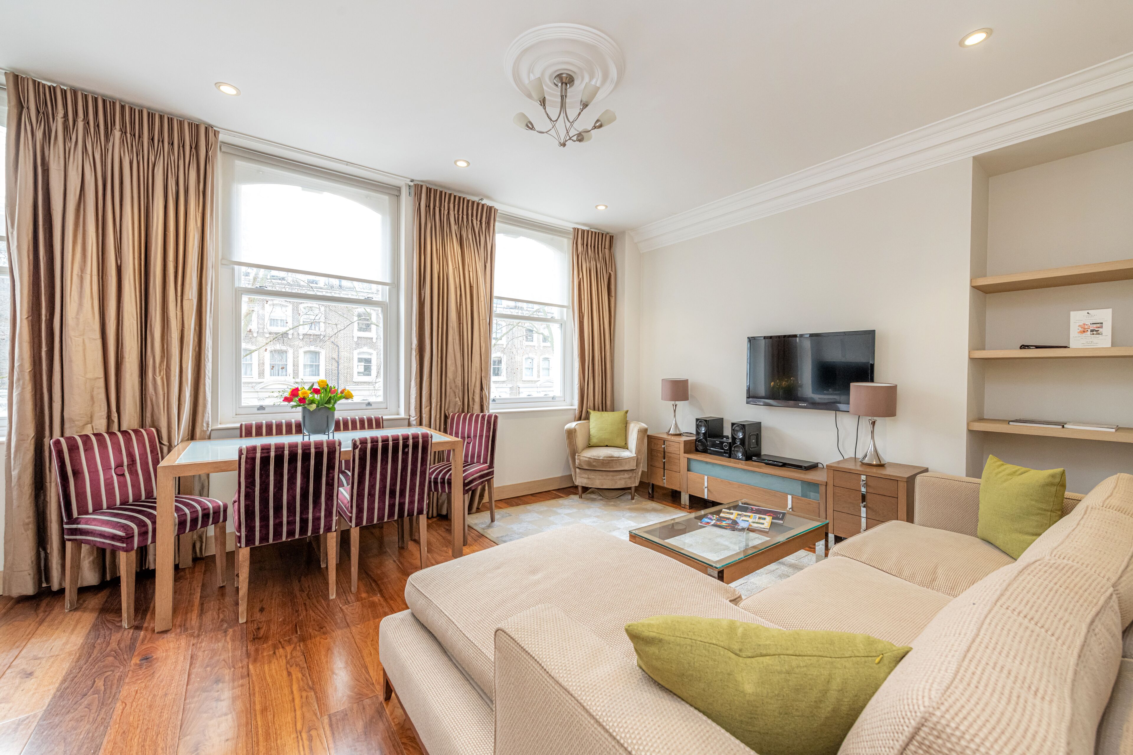 A modern living room with a sofa, dining table, chairs, and a television.