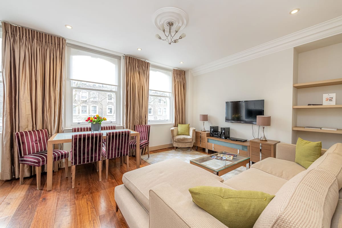 A modern living room with a sofa, dining table, chairs, and a television.