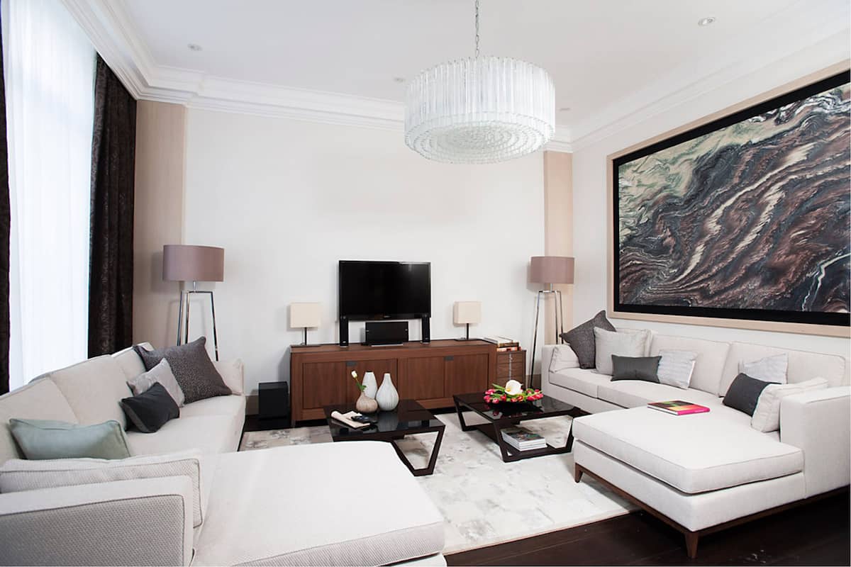 A modern living room with a large flat-screen TV, a white sofa, a coffee table, and a large abstract painting on the wall.
