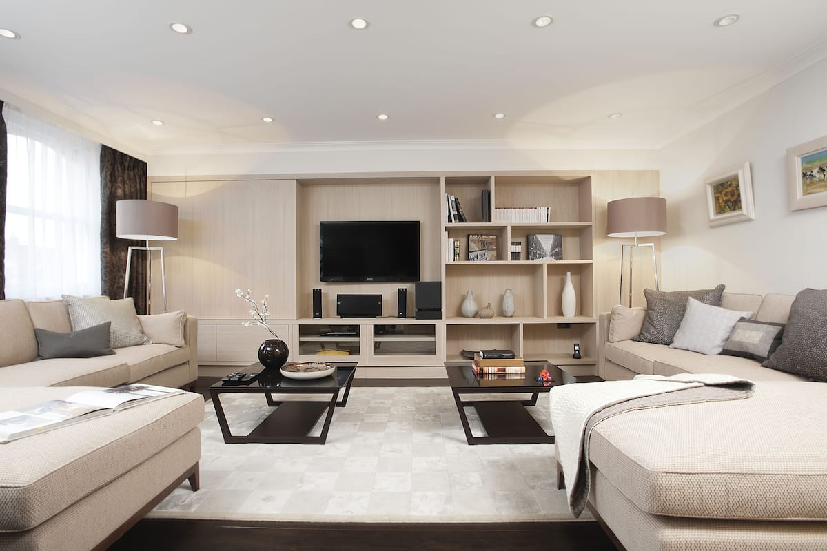 A modern living room with a sofa, two armchairs, a coffee table, a TV, and built-in shelving.