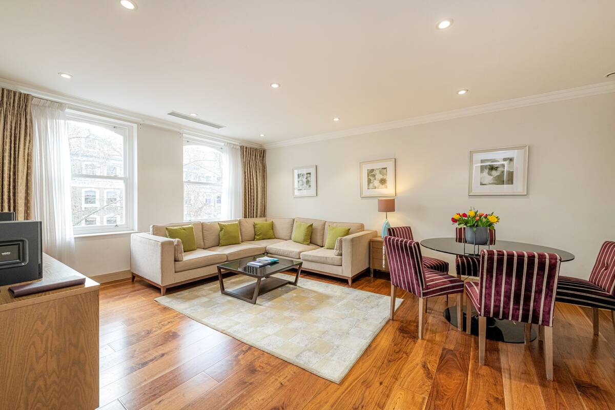 A modern living room with a sofa, coffee table, and striped chairs around a glass-top table.